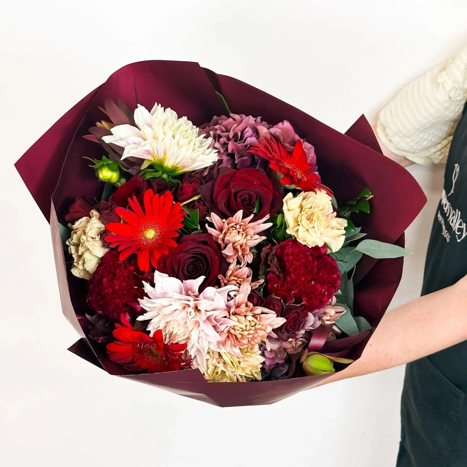 Midnight Ruby bouquet in Standard size with red roses, dahlias, and carnations wrapped in burgundy paper