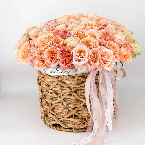 Handcrafted arrangement of 100 premium garden roses in woven basket with Flowers Valley ribbon