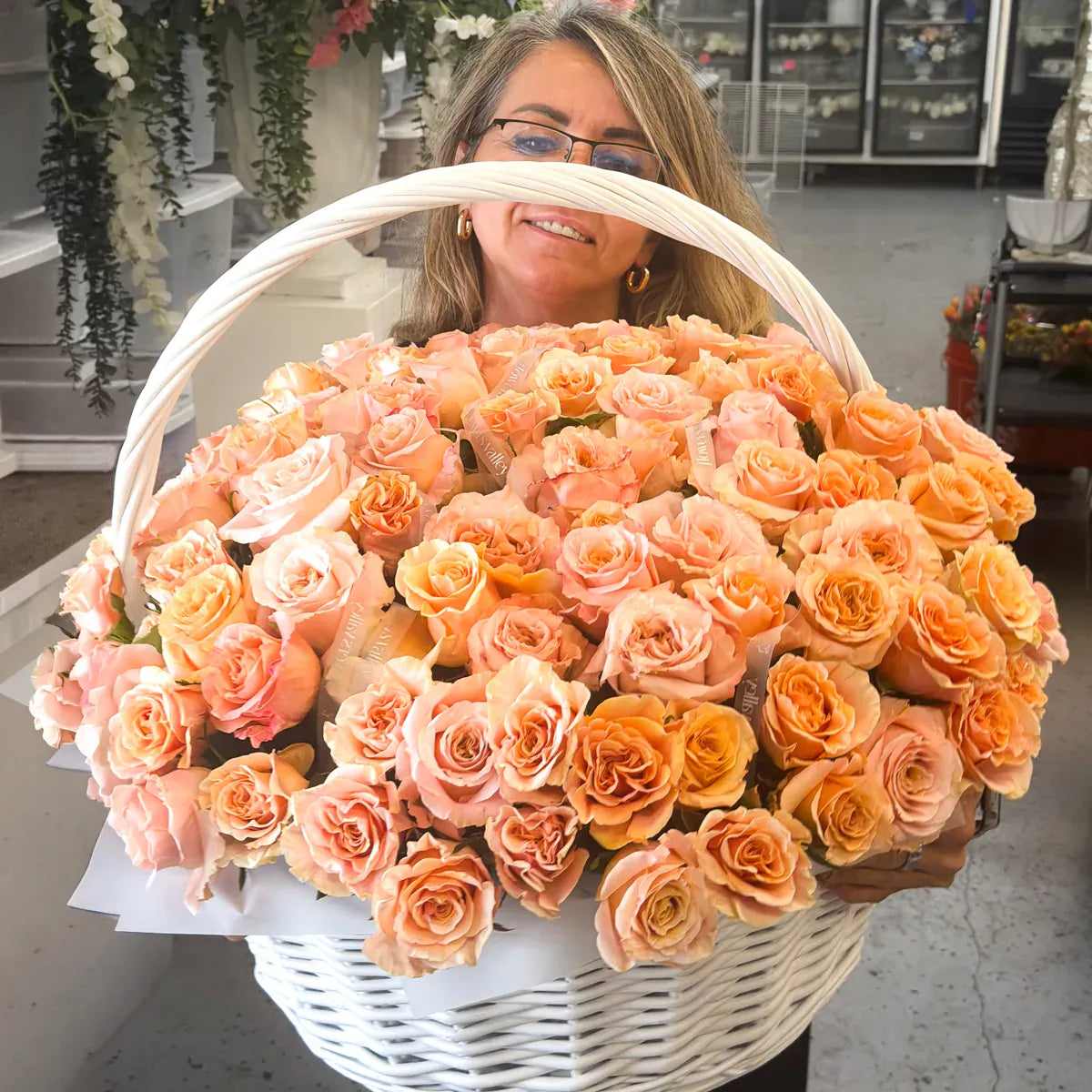 Helen, lead florist and founder of Flowers Valley is holding a large basket of peach-colored garden roses in our studio.