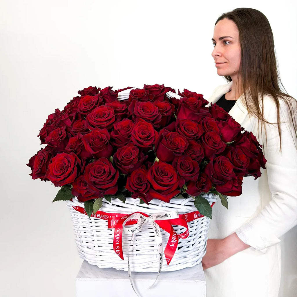 Woman holding a large white basket of 100 red roses - premium Flowers Valley ribbons