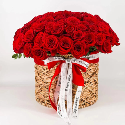 Handcrafted arrangement of 100 red roses in woven basket with Flowers Valley ribbon