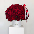 100 red roses arranged in a white hatbox with red and white ribbon from Flowers Valley