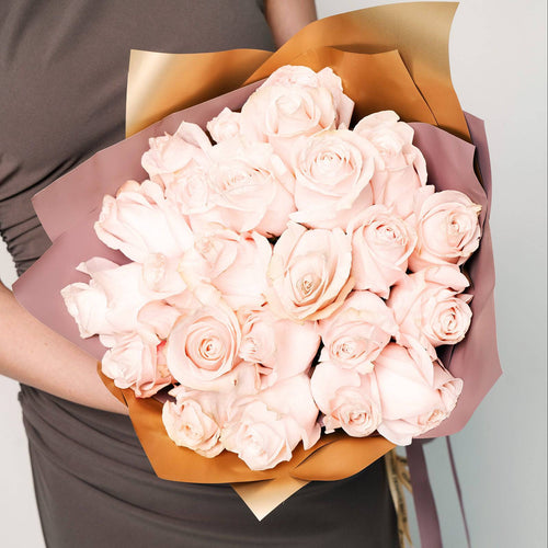 24 blush cream roses wrapped in tan and white paper with satin ribbon
