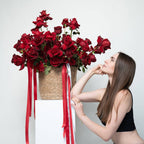 Person presenting a tall flower box with an overflowing display of red roses—perfect for dramatic gifting.