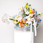 Morning Bloom bouquet with pastel ranunculus, roses, and mimosa in white vase
