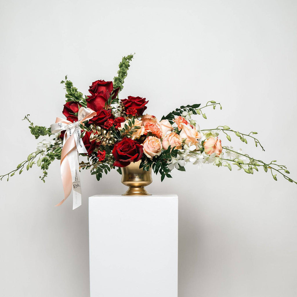 Opulent Romance bouquet with red and blush roses in a gold vase