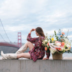 Woman holding large spring flower basket with pastel blooms outdoors