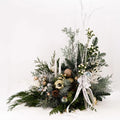Luxury holiday centerpiece with frosted evergreens, white berries, gold and silver ornaments, and two white taper candles, handcrafted by Flowers Valley.
