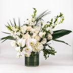 Bouquet of white flowers with greenery in a clear vase on a light background