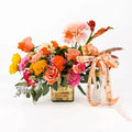 Harvest Sunset floral design featuring dahlias, roses, carnations, and celosia with orange accents in a gold vase.