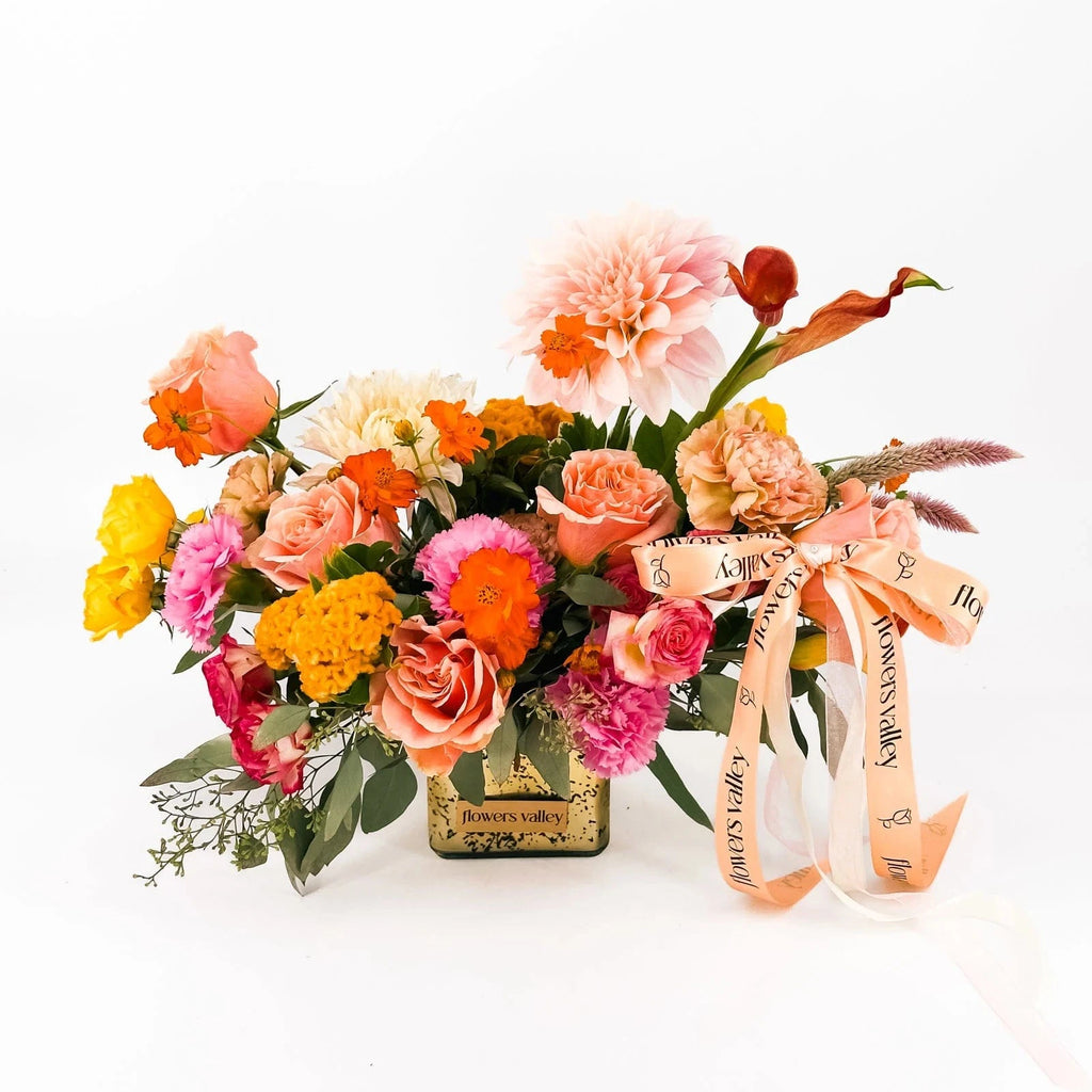 Harvest Sunset arrangement with dahlias, roses, celosia, carnations, and orange cosmos in a gold vase by Flowers Valley.
