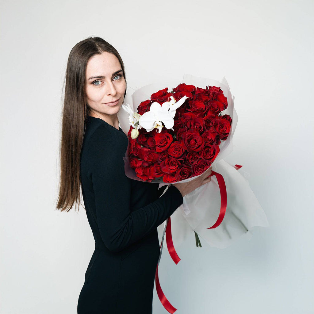 Woman holding Orchid Embrace rose and orchid bouquet wrapped for gifting