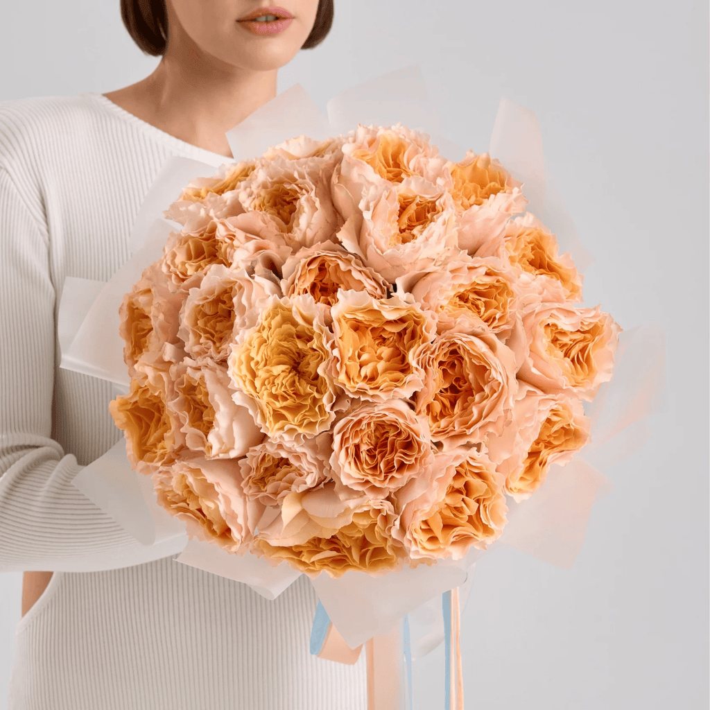 Hand-tied bouquet of peach garden roses wrapped in soft cream paper