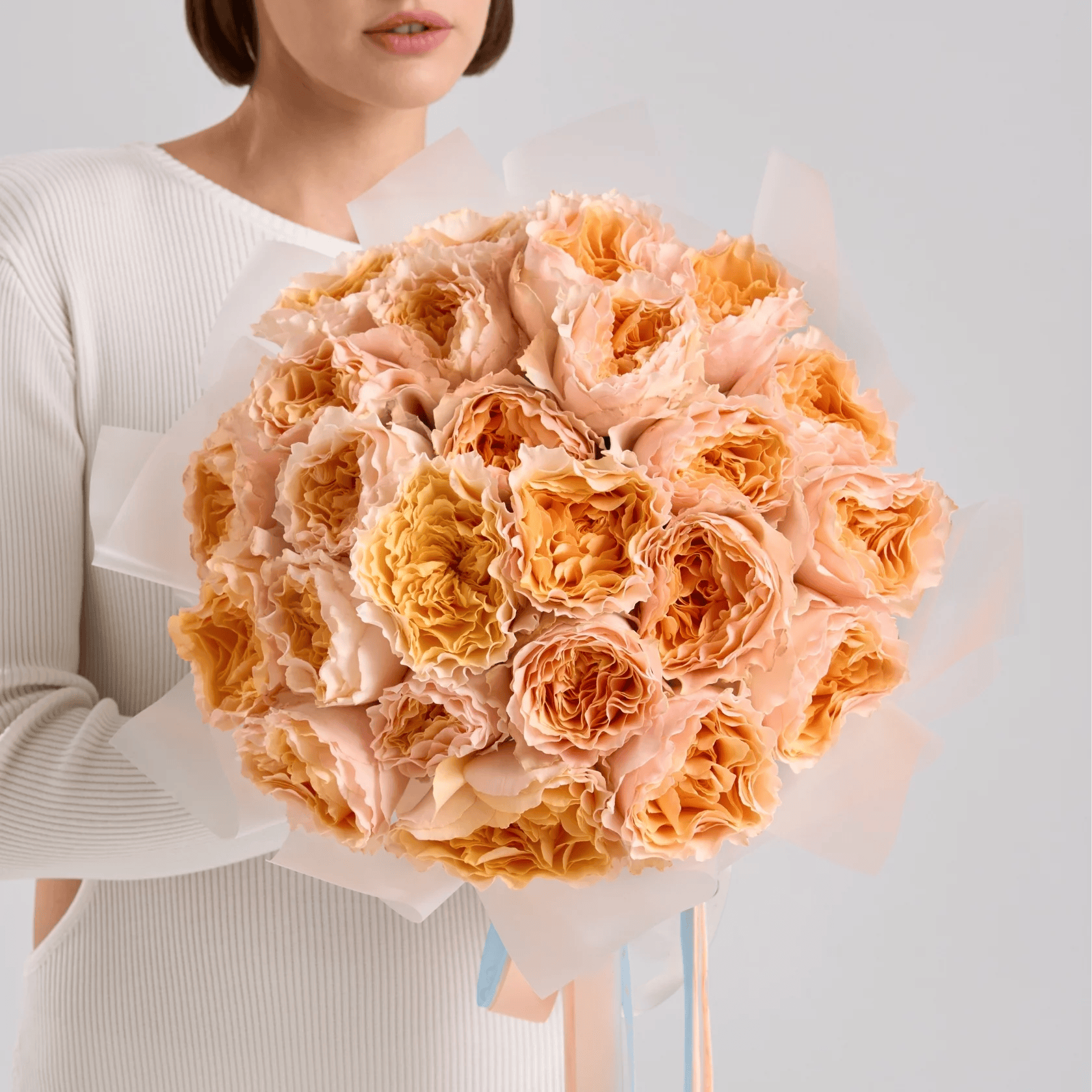 Hand-tied bouquet of peach garden roses wrapped in soft cream paper