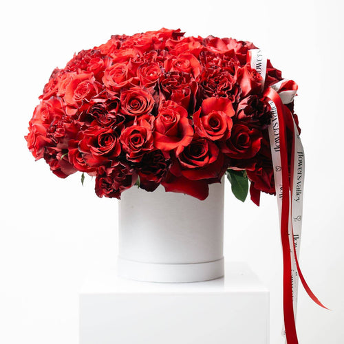 100 mixed red roses arranged in a white Flowers Valley signature box with ribbon