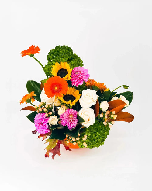 Top view of Autumn Cheer Pumpkin Arrangement showing vibrant blooms and pumpkin vessel