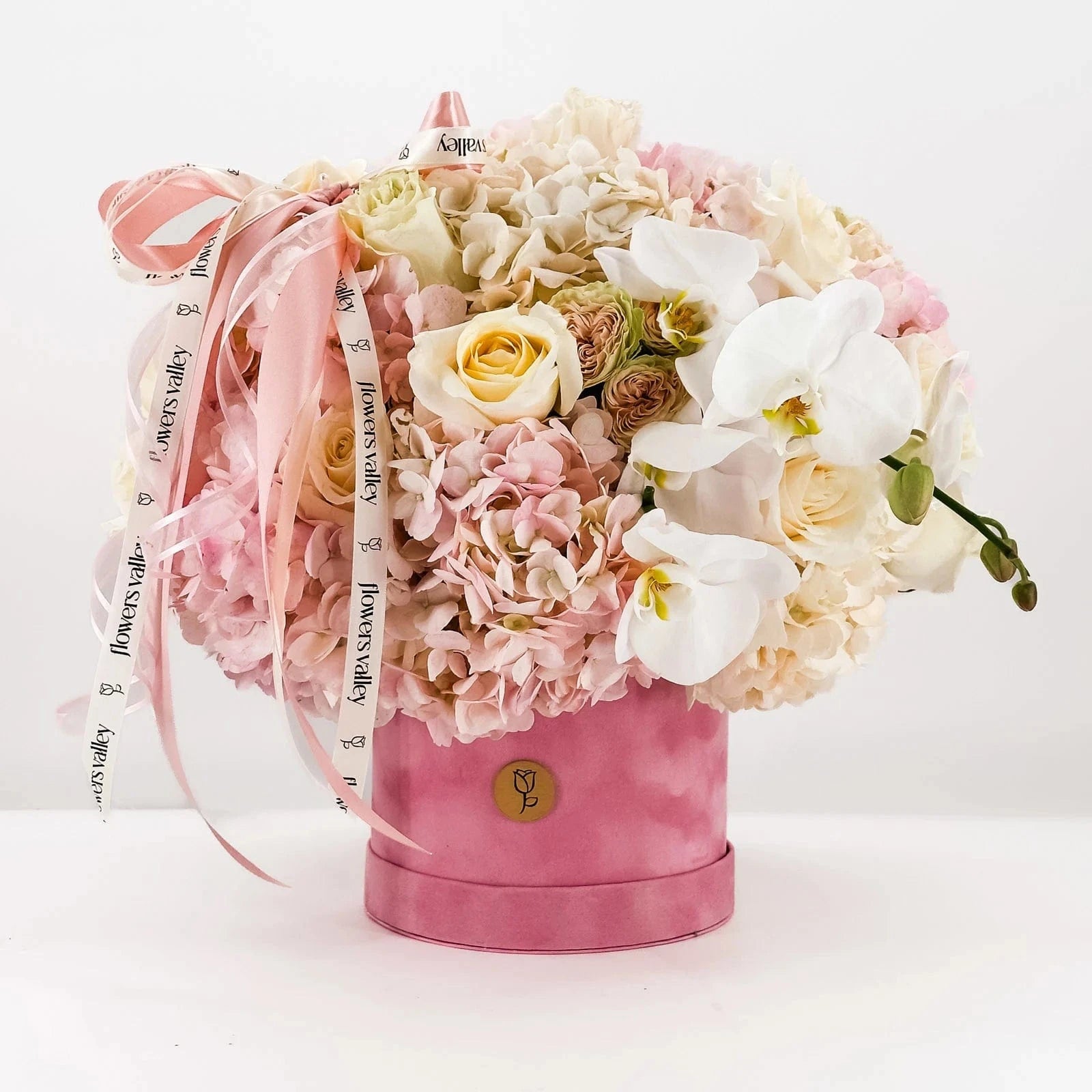 Baby Girl Bloom Box with pastel hydrangeas, roses, orchids, and pink velvet hatbox