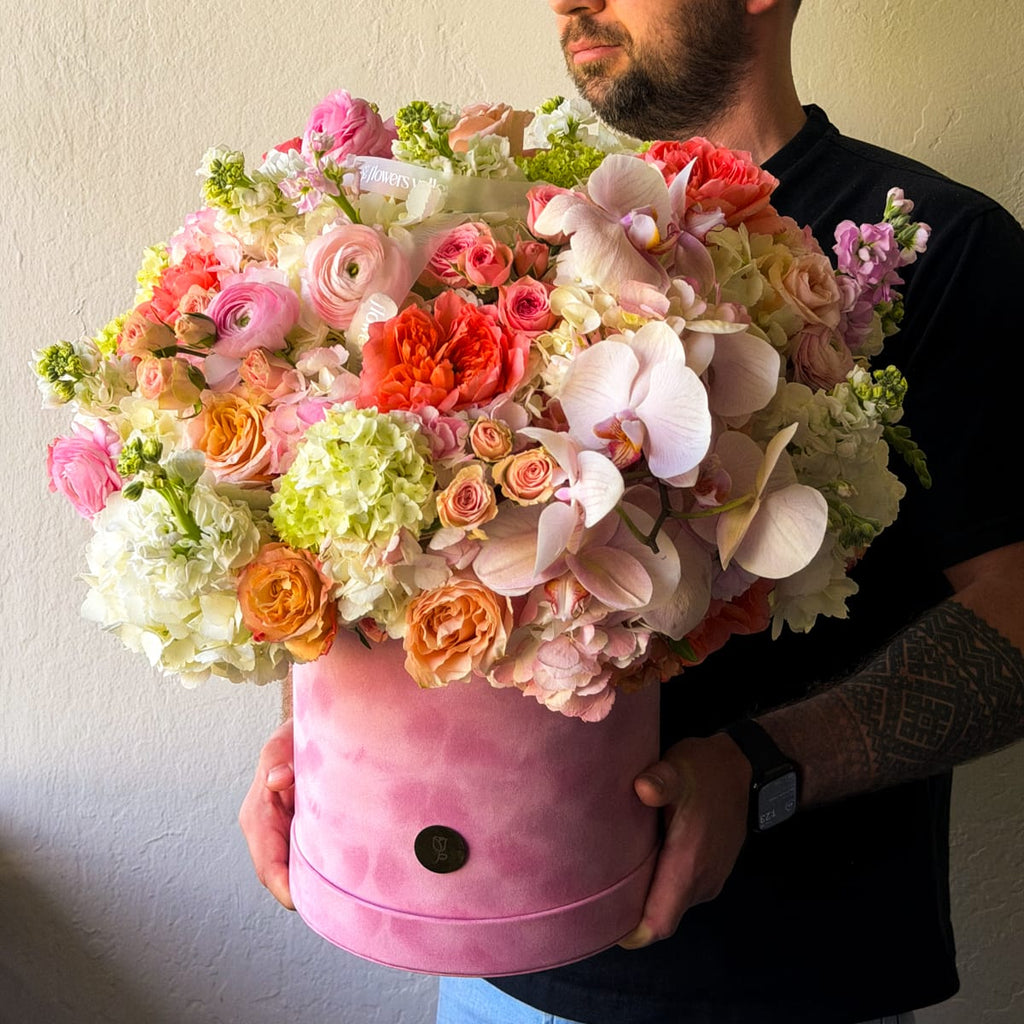 Person holding Blush Elan Flower arrangement in a velvet pink Hat Box 