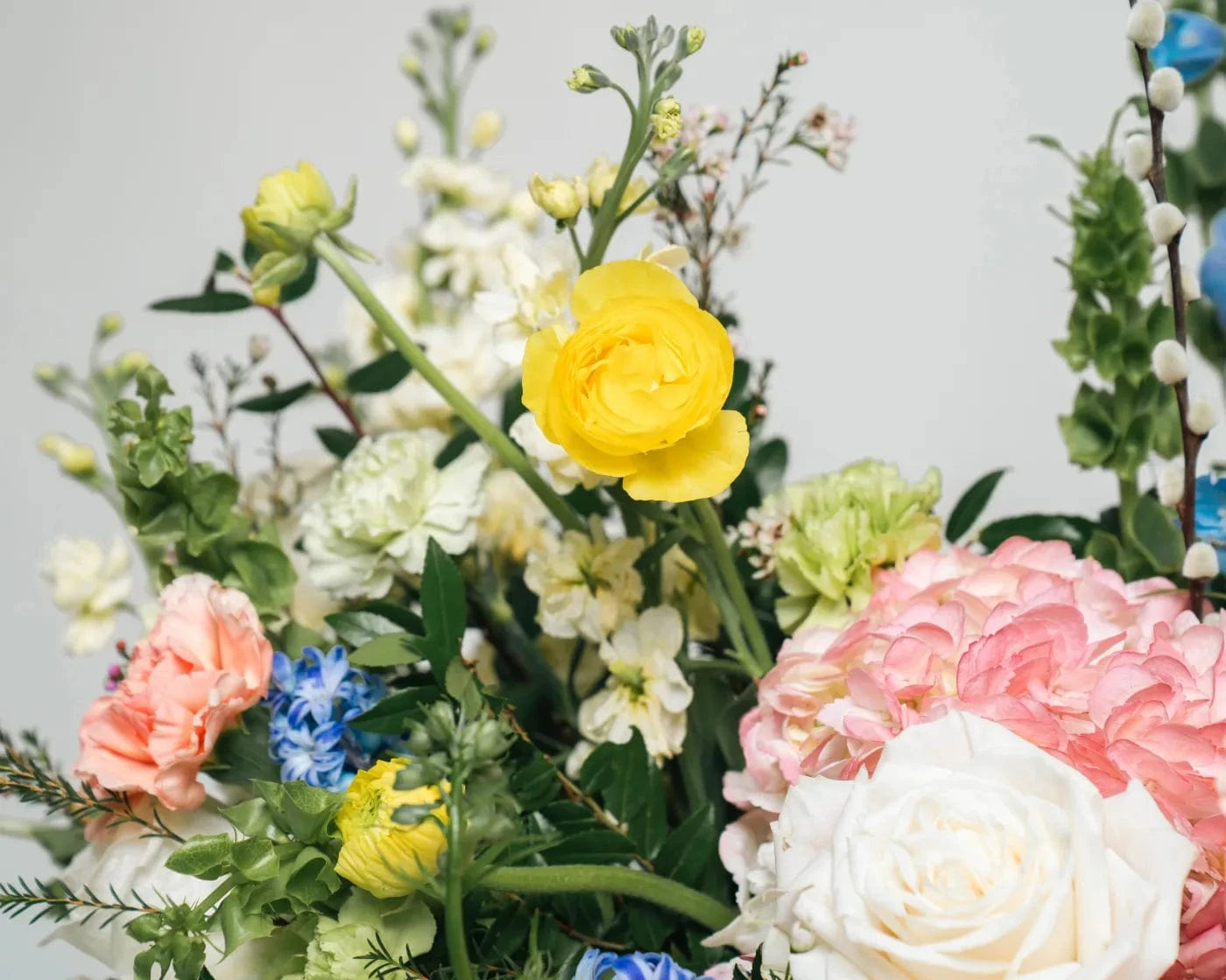 Bright flower arrangement with yellow ranunculus, pink peonies, hydrangeas, and blue delphiniums – Flowers Valley flower delivery in Daly City, CA