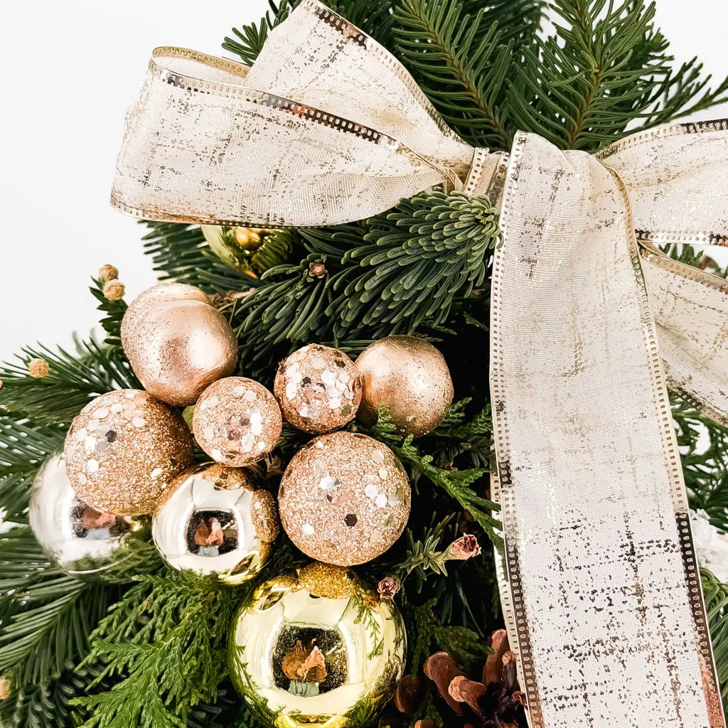 Close-up of champagne and gold ornaments with ivory ribbon on the Champagne Glow Tree, handcrafted holiday décor by Flowers Valley.