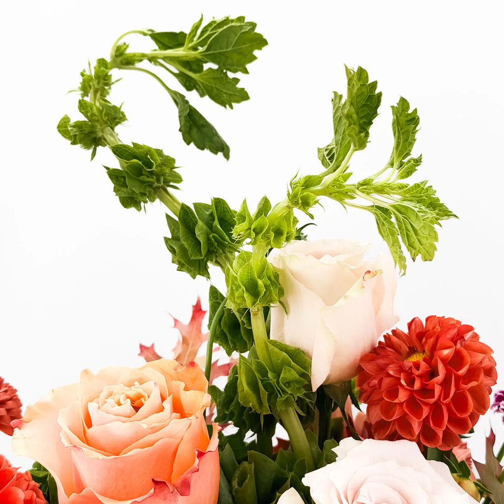 Close-up of Cinnamon Bloom Arrangement highlighting orange dahlias and blush roses