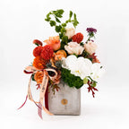 Cinnamon Bloom Arrangement with roses, dahlias, and orchids in a stone vase