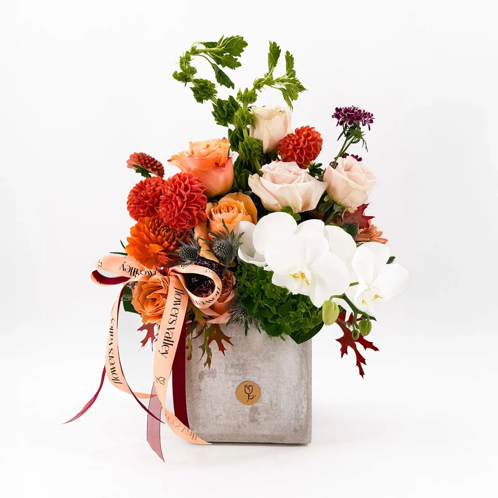 Cinnamon Bloom Arrangement with roses, dahlias, and orchids in a stone vase
