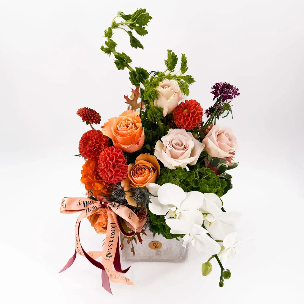 Side view of Cinnamon Bloom Arrangement with peach roses and white orchids