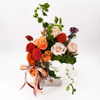 Side view of Cinnamon Bloom Arrangement with peach roses and white orchids