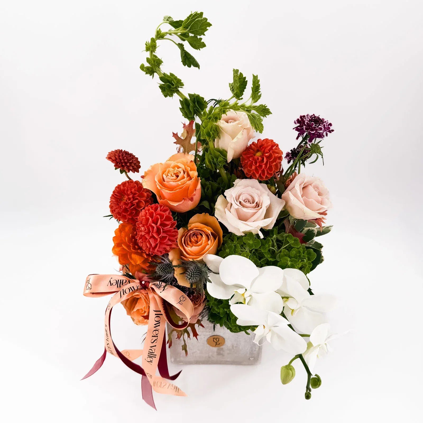 Side view of Cinnamon Bloom Arrangement with peach roses and white orchids