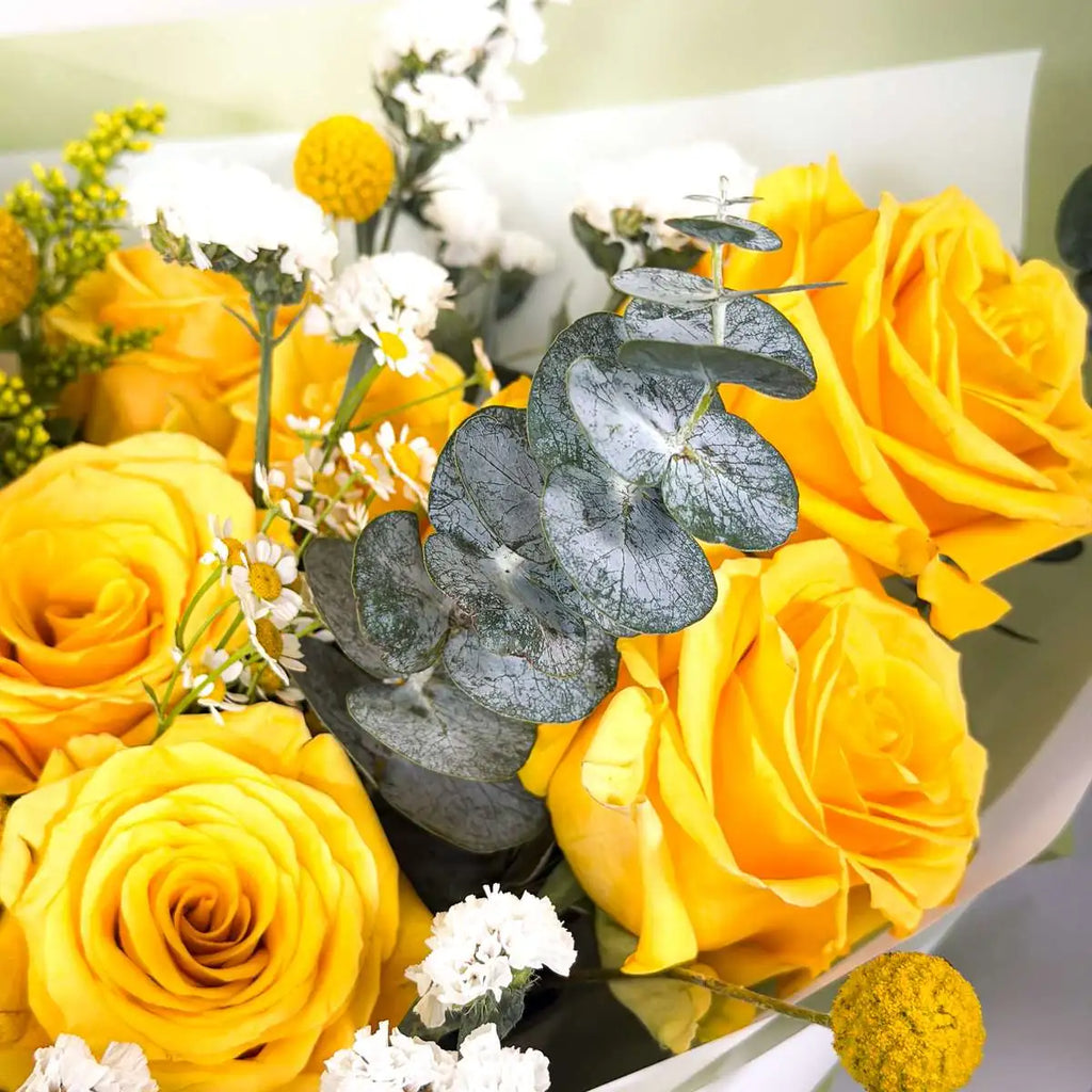 Close-up of yellow roses, eucalyptus, craspedia and white statice in the Citrine bouquet by Flowers Valley
