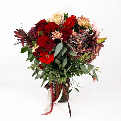 Crimson Charm bouquet with red and burgundy flowers, hydrangeas, and greenery in a clear vase – Flowers Valley