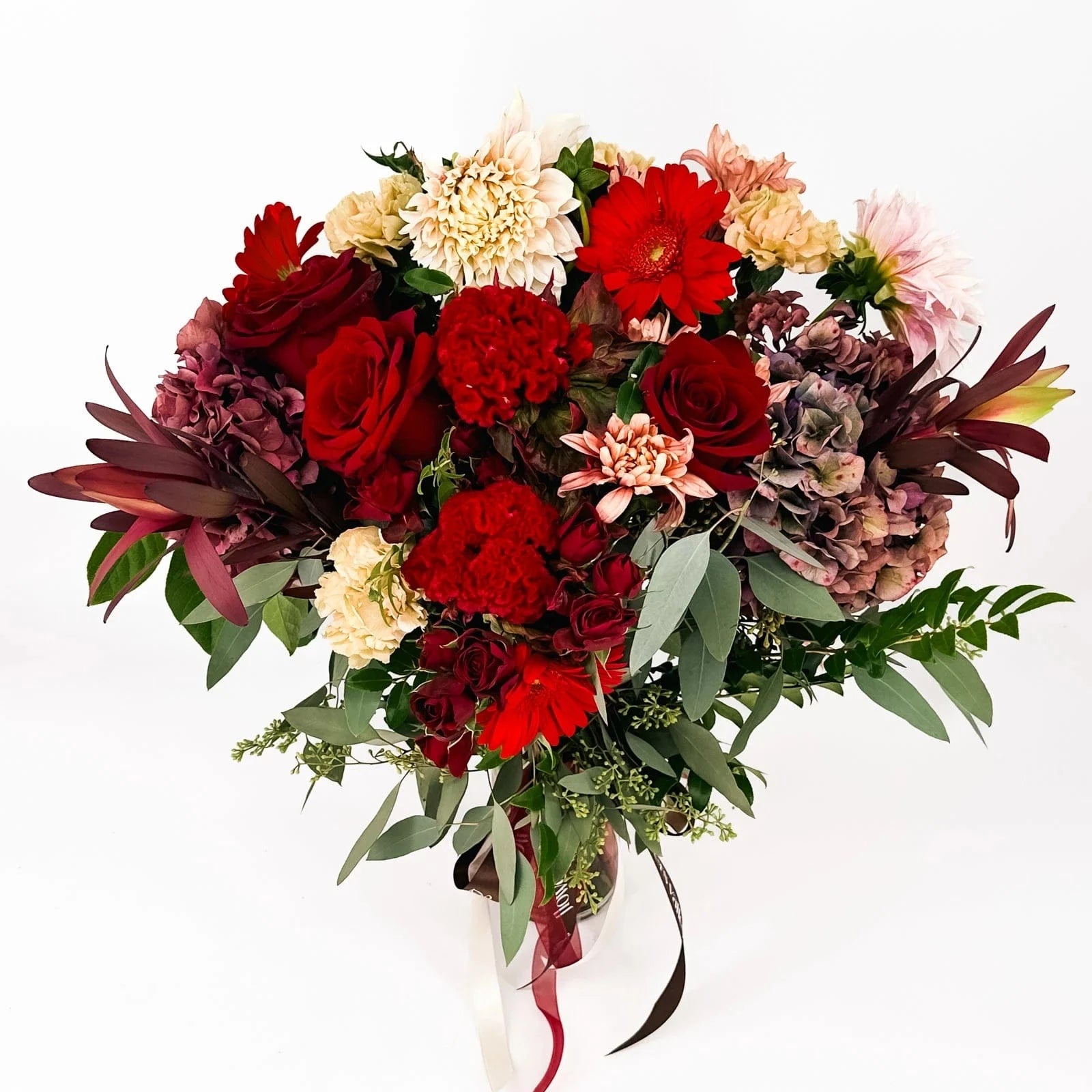 Close-up of Crimson Charm bouquet with red roses, dahlias, carnations, and gerbera daisies