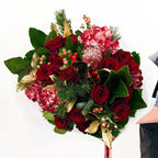 Crimson Majesty Bouquet with red roses, hydrangeas, protea, and holiday greenery