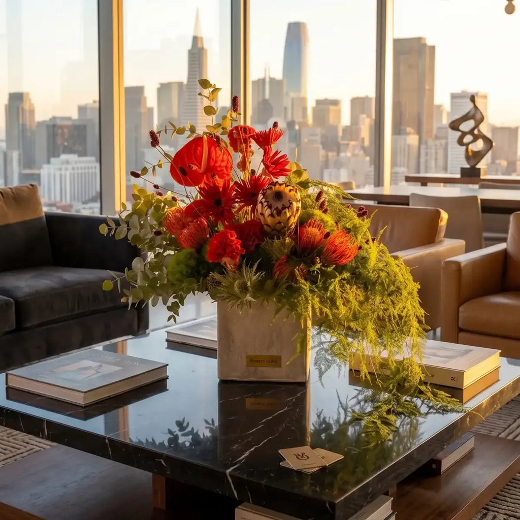 Ember & Stone arrangement with red protea and anthurium styled on a modern coffee table with San Francisco skyline view