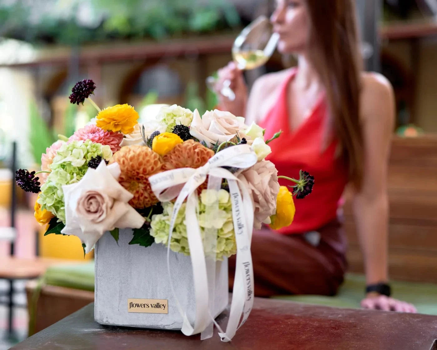 Chic flower arrangement in a white box with roses, hydrangeas, and ranunculus on a table at an outdoor café – luxury same-day flower delivery in Danville, CA by Flowers Valley