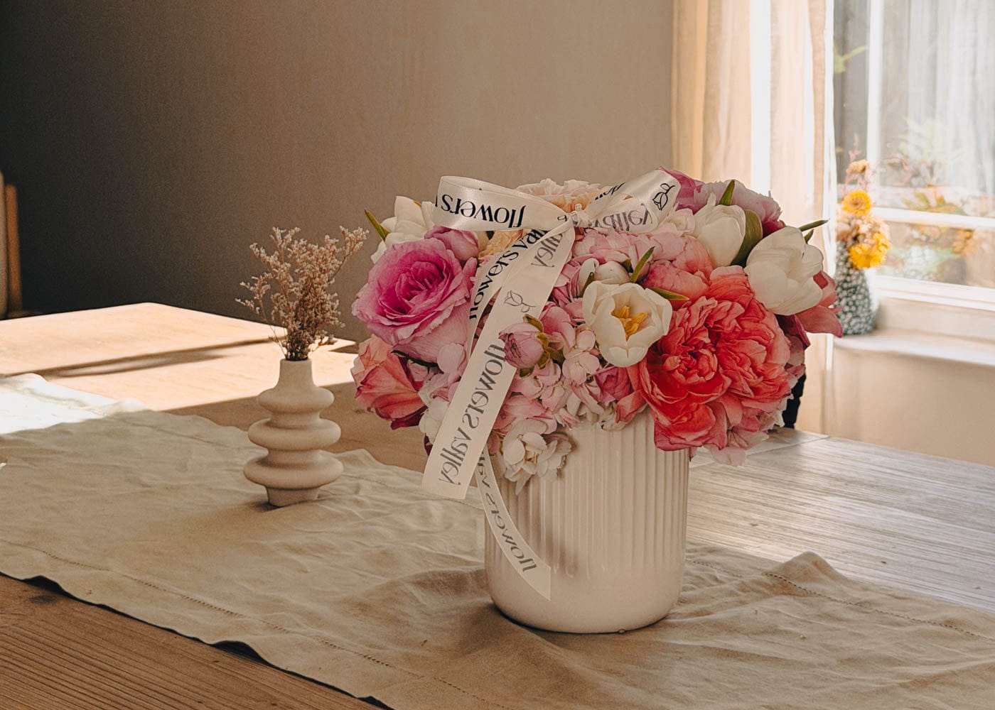 Bouquet of flowers in a vase on a table with a neutral background - Flower Subscription delivered weekly