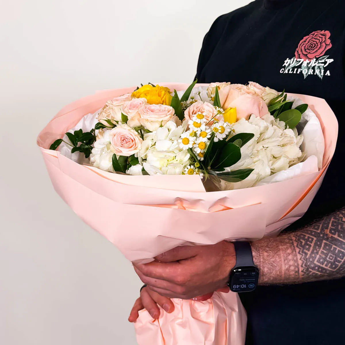 Bouquet of flowers held by a person wearing a black shirt with a logo.