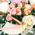 Close-up of white roses, blush spray roses, and orchids in a sympathy floral design