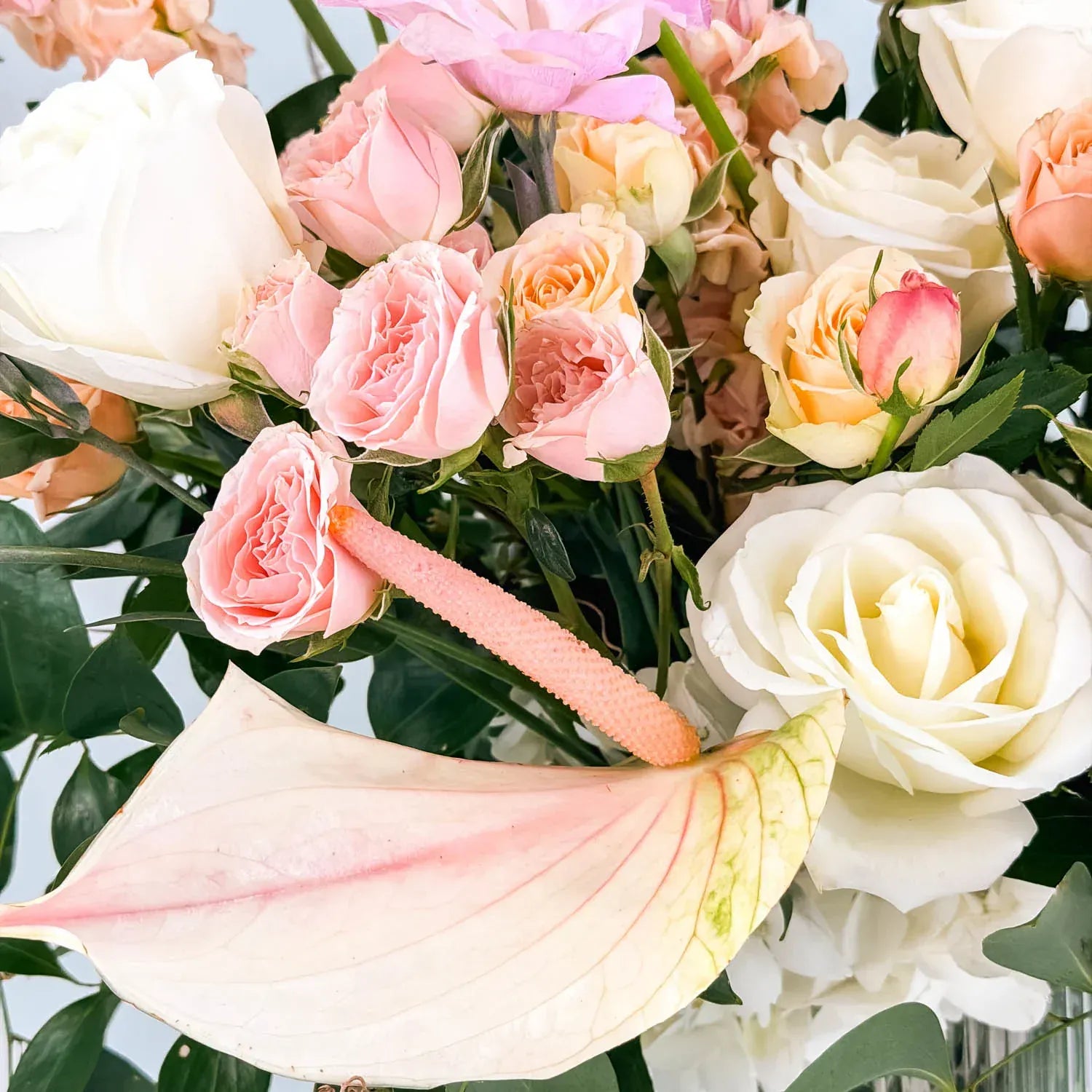 Close-up of white roses, blush spray roses, and orchids in a sympathy floral design