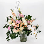 Sympathy flower arrangement with white roses, orchids, and soft blush blooms in a glass vase