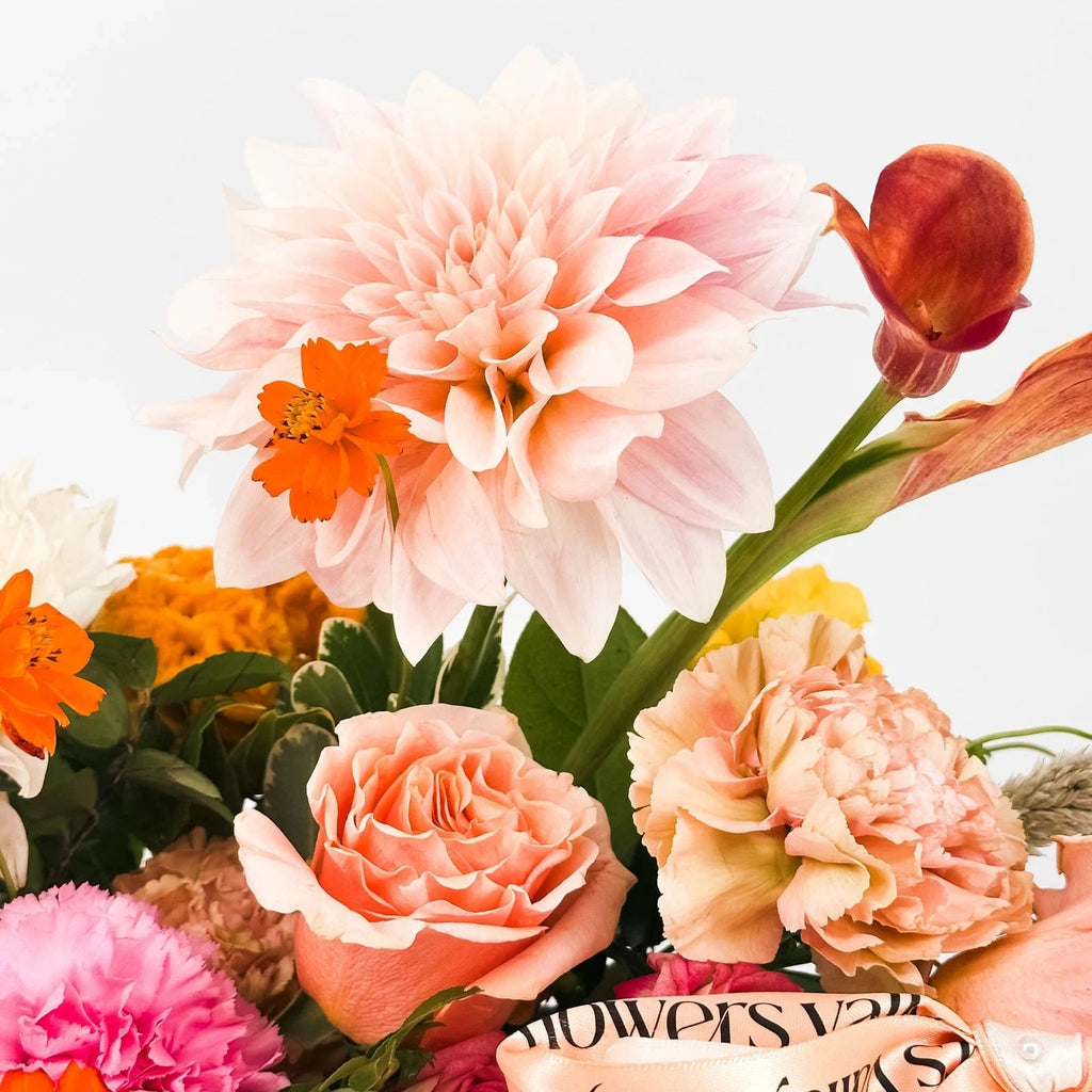 Close-up of blush dahlia with peach roses, celosia, and calla lily from the Harvest Sunset arrangement.