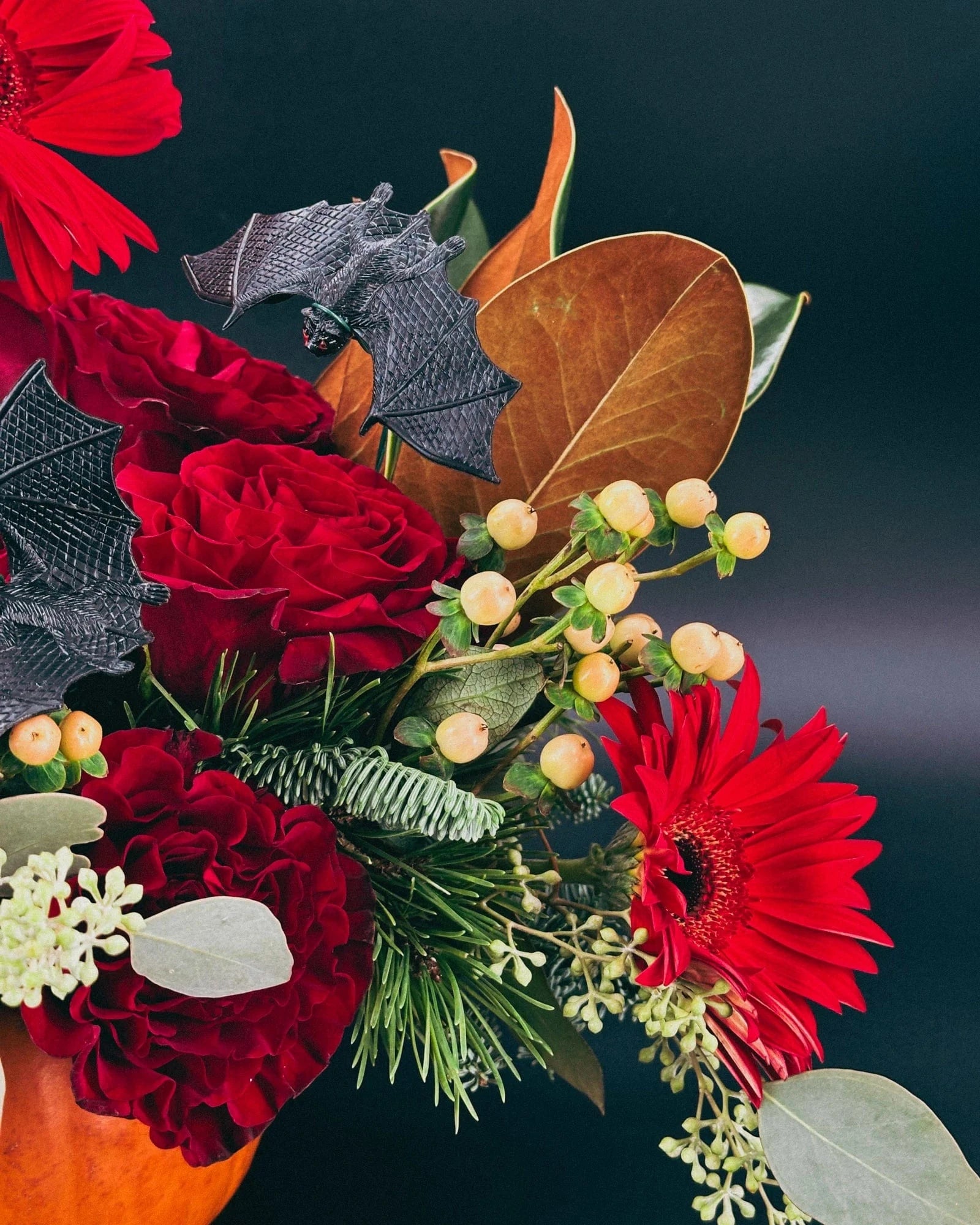 Close-up of Haunted Elegance Pumpkin Arrangement featuring skull, bats, and red gerbera daisy