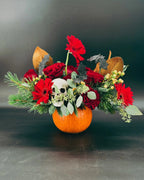 Haunted Elegance Pumpkin Arrangement with skull, bats, and red flowers against dark background
