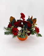 Halloween flower arrangement with pumpkin vase, skull, red roses, and bats