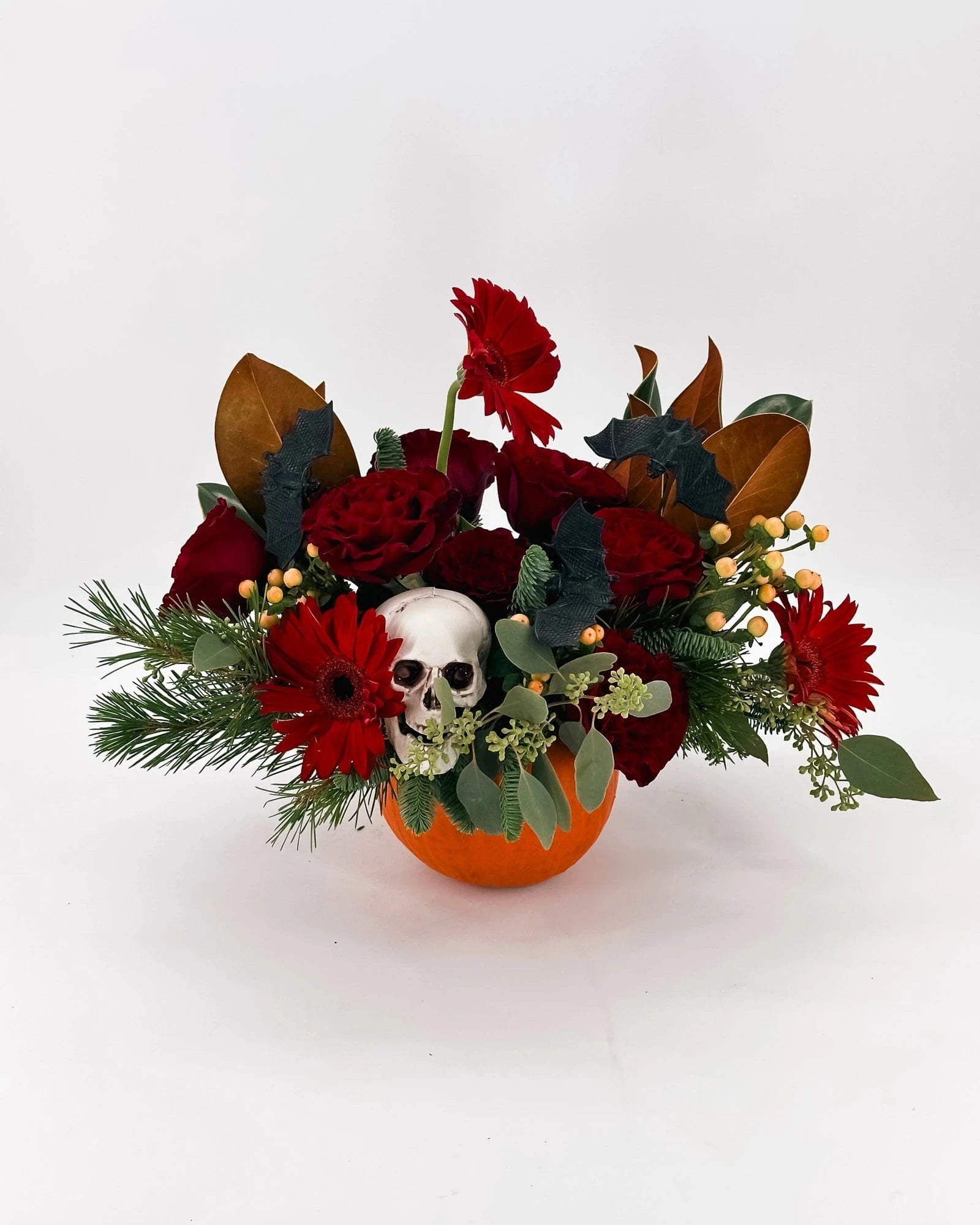 Halloween flower arrangement with pumpkin vase, skull, red roses, and bats