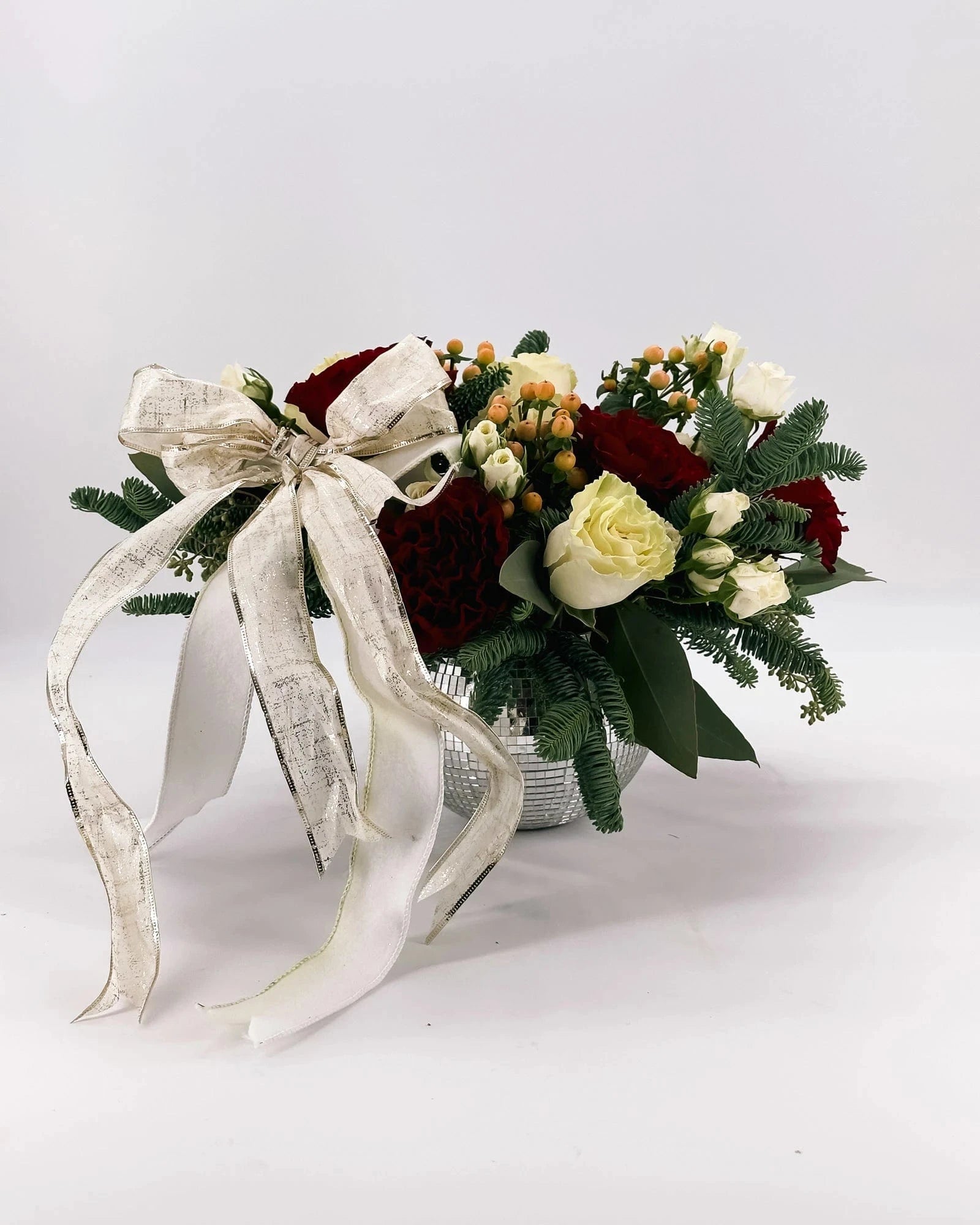 Holiday Enchantment Arrangement with red and white roses, gold ribbon, and festive greenery