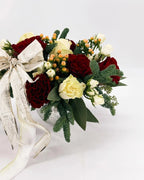 Side view of Holiday Enchantment Arrangement with roses, berries, evergreens, and gold bow