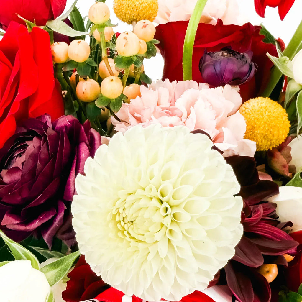 Close-up of Holiday Muse Arrangement showing white dahlia, roses, and holiday accents