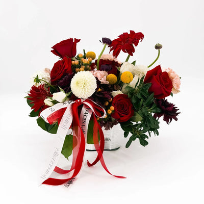 Side view of Holiday Muse Arrangement with red, white, and burgundy flowers